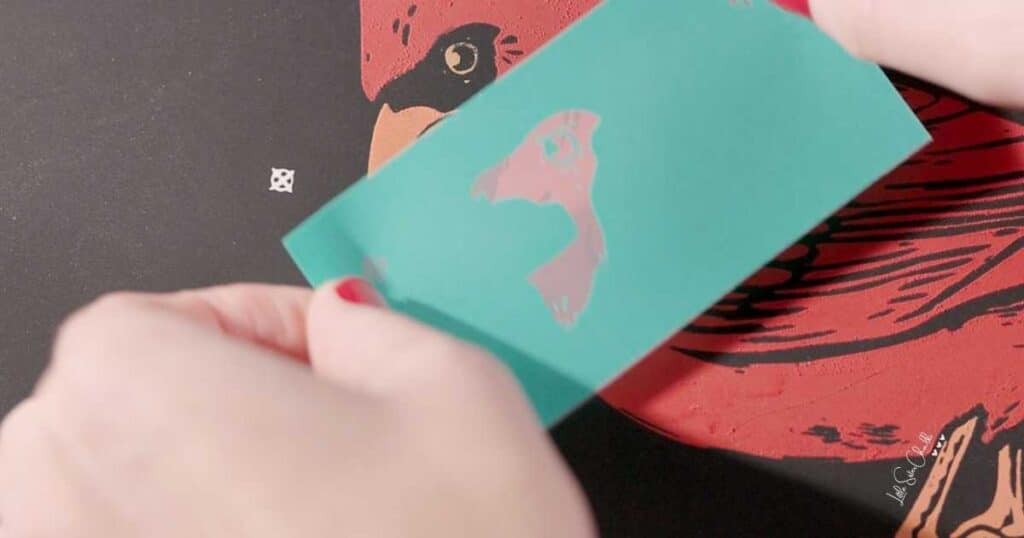 A close up of a chalked cardinal with a stencil over it showing registration marks to align the stencil with the design for the blog post Give these 10 Hottest Chalk Couture Techniques a Try