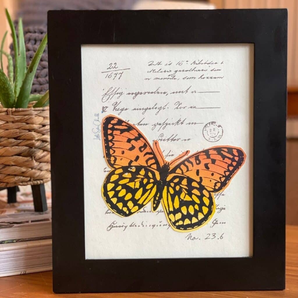Watercolor paper with words and a stamp chalked on with grey chalk paste with cut out watercolor butterfly in a back frame for blog post Try Your Hand at Watercoloring with Chalk Couture