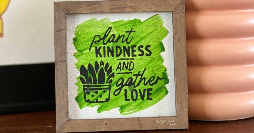 Close up of small wooden frame color washed with watered down green chalk paste with words "plant kindness and gather love" with a small plant chalked on frame in black chalk paste for blog post Try Your Hand at Watercoloring with Chalk Couture
