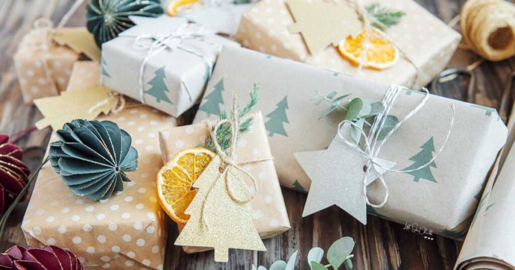 Various packages wrapped in polka dot paper and paper with green Christmas trees with tree and star tags surrounded by slices of orange for blog post Chalk Couture Black Friday Deals