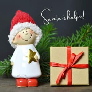 Little Christmas elf dressed in white with a red hat and red shoes holding a gold start next to a gift wrapped in brown paper with a red bow with the words "Santa's helper!" for blog post The Official Little Sister Chalks Gift Guide