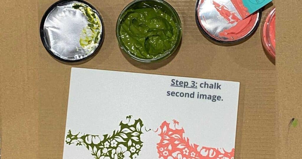 Image of a bird chalked in green chalk paste and its mirror image chalked in coral chalk paste and an open jar of green chalk paste and the lid of coral chalk paste with a squeegee in it with the words "Step 3: chalk second image" for the blog post Creating Mirror Images Using Chalk Couture