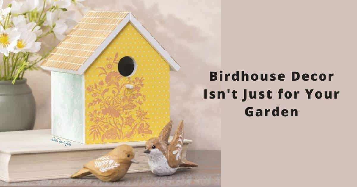 A photo of the Chalk Couture Birds of a Feather ChalkMade Kit finished project in yellow, eggshell blue and camel, sitting on top of a book with two bird figurines in front and white flowers in a grey vase to the left for the blog post "Birdhouse Decor Isn't Just for Your Garden".