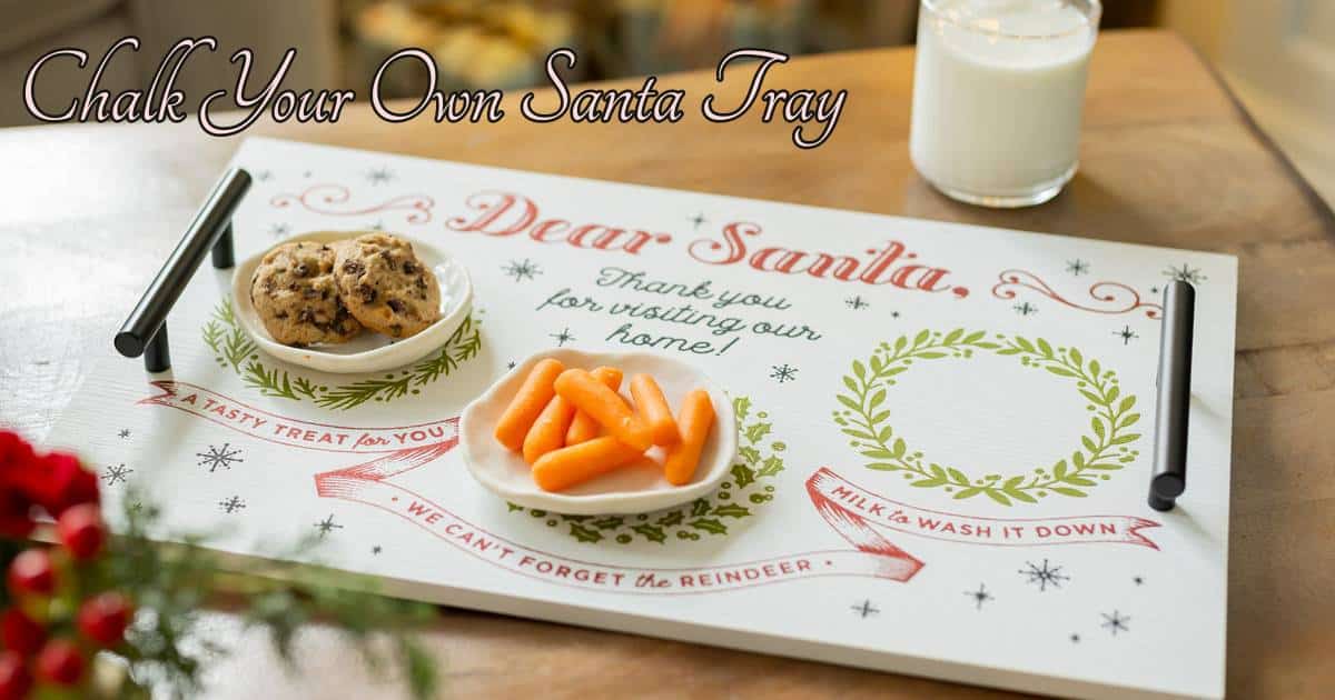 The finished Santa Tray ChalkMade Kit project on a coffee table flanked by a glass of milk with the words "Dear Santa, thank you for visiting our home! A tasty treat for you. We can't forget thee reindeer. Mile to wash it down." with two small plates on the tray holding chocolate chip cookies and carrots for the blog post "Chalk your own Santa Tray".