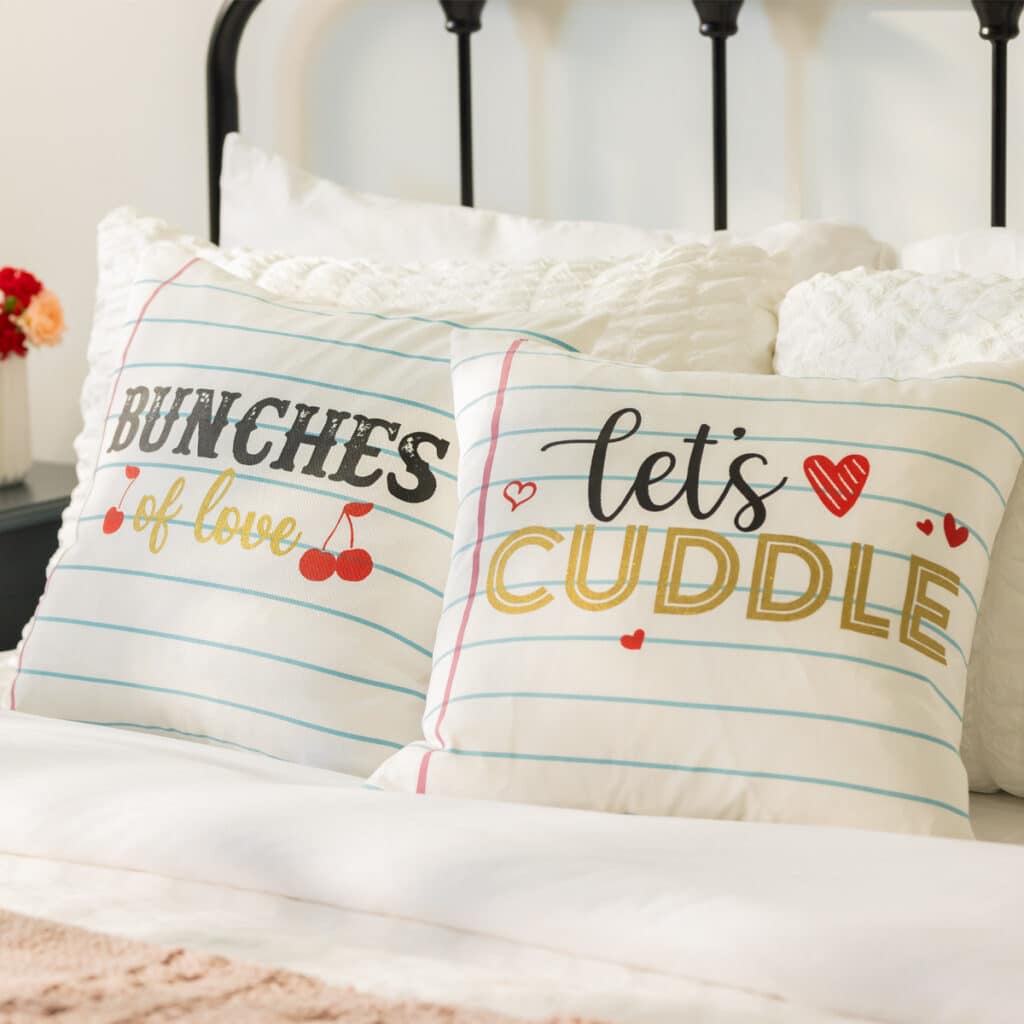 Two pillows on a bed that look like notebook paper with "Bunches of Love" on one and "Let's Cuddle" on the the other.
