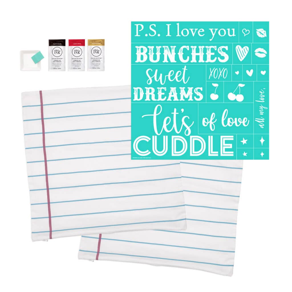 Contents of the Chalk Couture Let's Cuddle Kit showing 2 notebook pillowcases, 1 stencil, 3 ink packets, 3 color trays and a squeegee. 