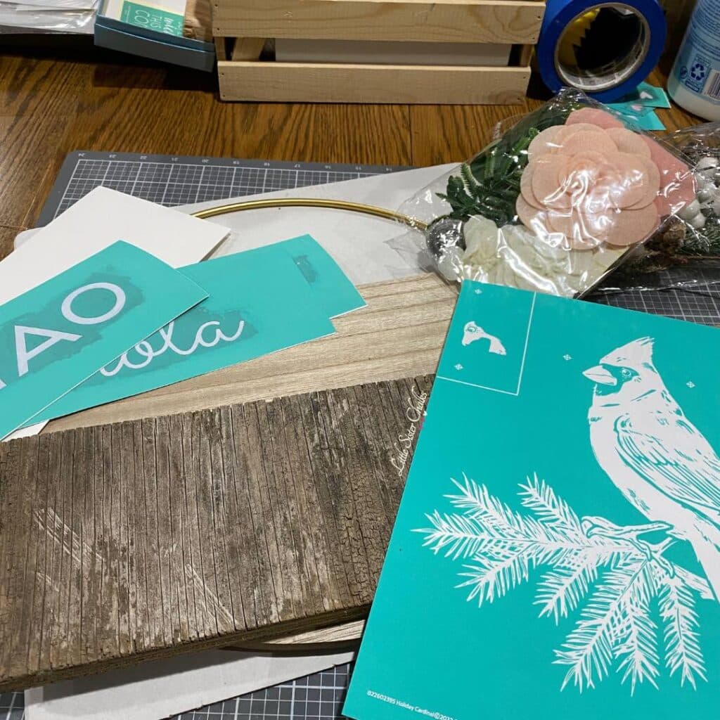 A table holding craft supplies including Chalk Couture stencils, a piece of scrap wood, a Chalk Couture Hoop Wreath and embellishments for the blog post "DIY Scrap Wood Projects".