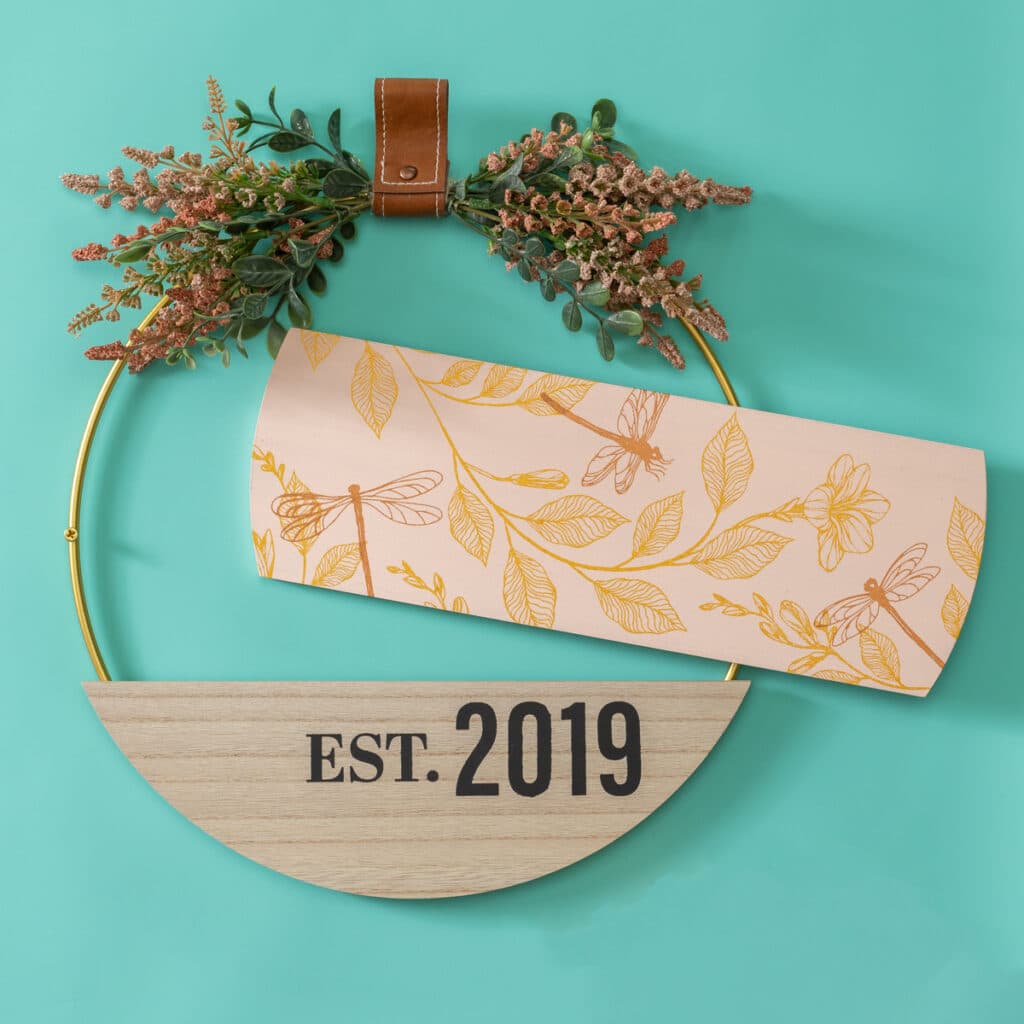 A 3 piece hoop wreath with dragonflies, foliage and "est 2019" on a turquoise background for the blog post "2024 Creative Kickstart Collection".