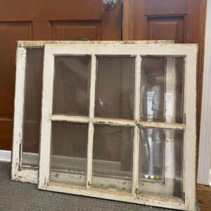 Two old windows with chippy cream paint sitting on the floor in front of a door for the blog post "An Old Window Gets New Life with Chalk Couture".