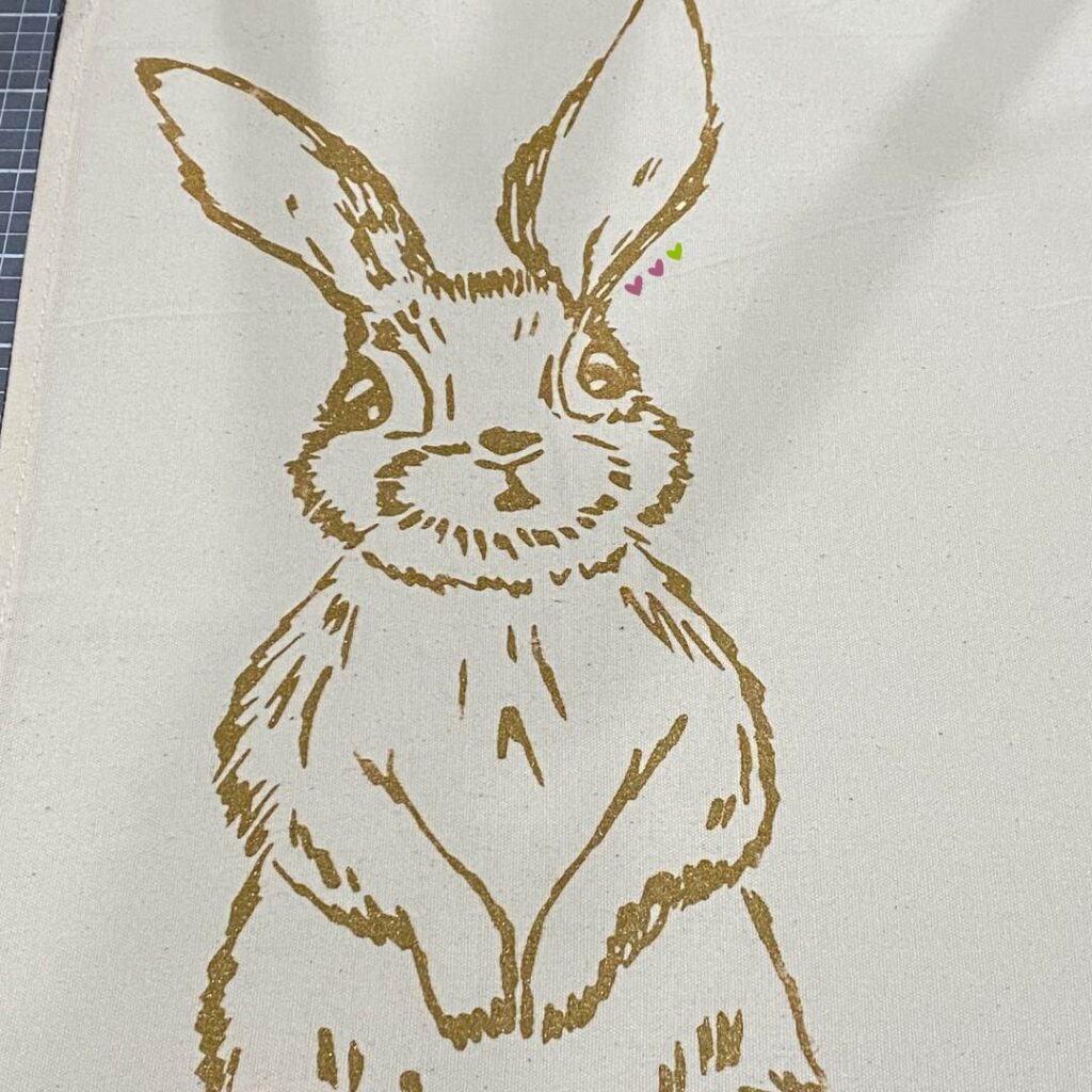 A bunny inked in Shimmer Copper Chalkology Ink on canvas fabric for the blog post "Nine Ways to Use a DIY Stuffed Bunny in Your Decor this Spring".