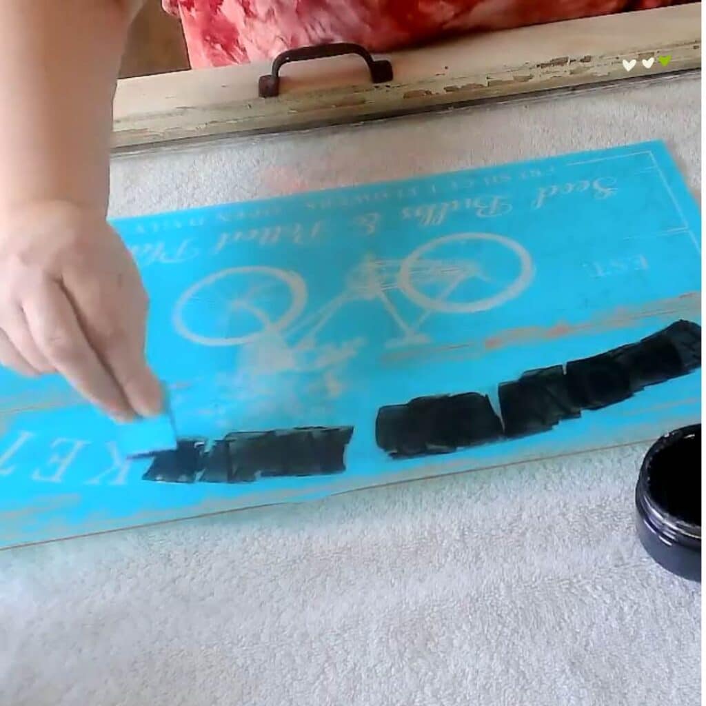 A woman's hand applying Black Velvet Chalk Couture Chalkology Paste to the Flower Market stencil on a window for the blog post "An Old Window Gets New Life with Chalk Couture".