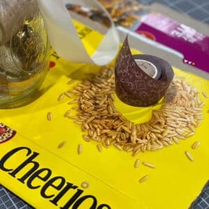A Cheerios box cut and folded into a file folder on a craft mat with a roll of brown washi tape with flowers sitting on top of the file folder for the blog post "Two Simple Ways to Reuse Cardboard Boxes Around Your Home".