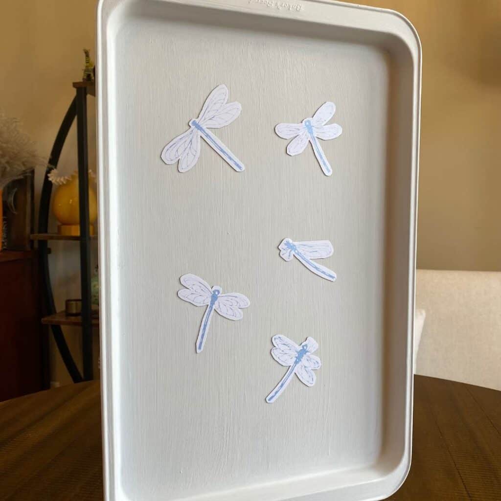 Five blue dragonfly magnets on the inside of a cookie sheet painted white for the blog post "How to Upcycle an Old Cookie Sheet with Chalk Couture".