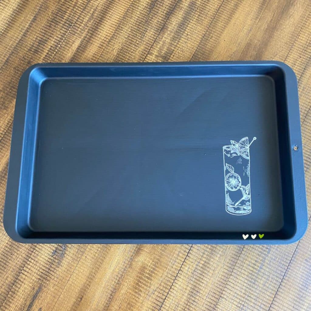 A cookie sheet upcycled into a serving tray by painting it black and applying a mojito cocktail stencil in bright white chalk paste in the lower right corner of the tray for the blog post "How to Upcycle an Old Cookie Sheet with Chalk Couture".