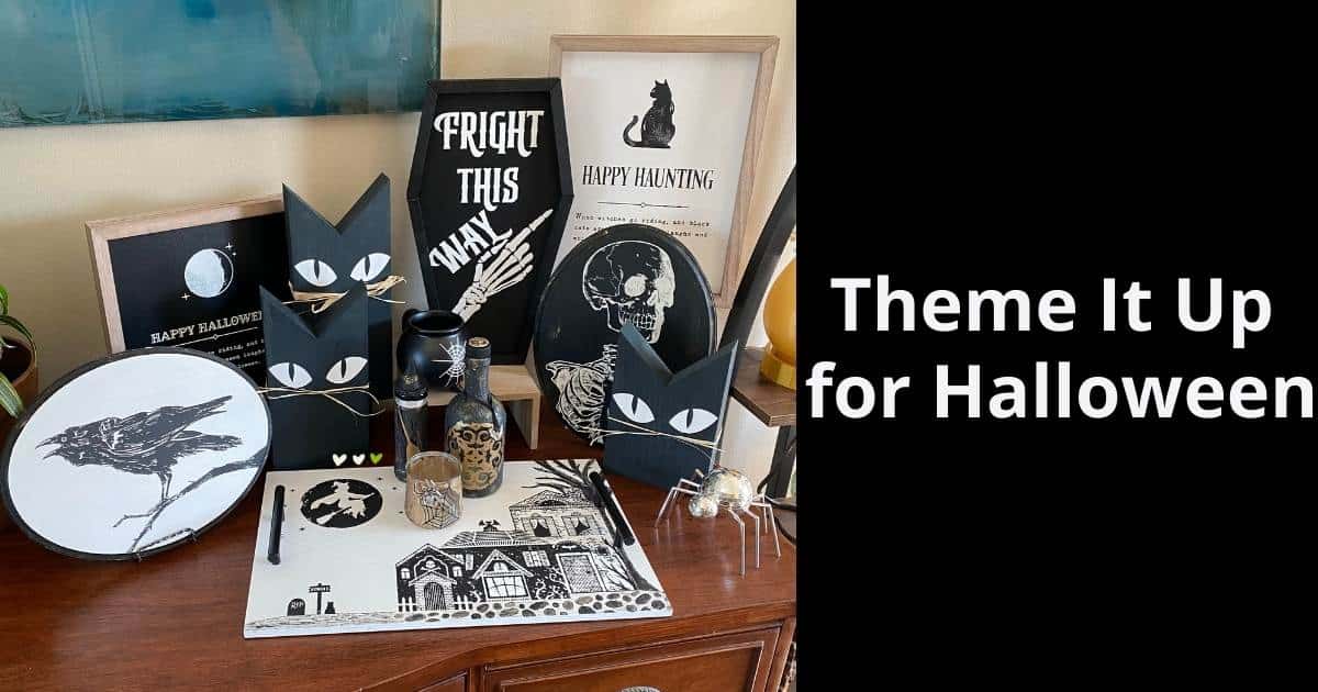 A picture of a back and white Halloween display with a wide variety of decor items from box frames, wooden black cats, ovals with a crow and skeleton, apothecary jars, a coffin and a tray with a witch flying over spooky houses flanked by the words "Theme It Up for Halloween".