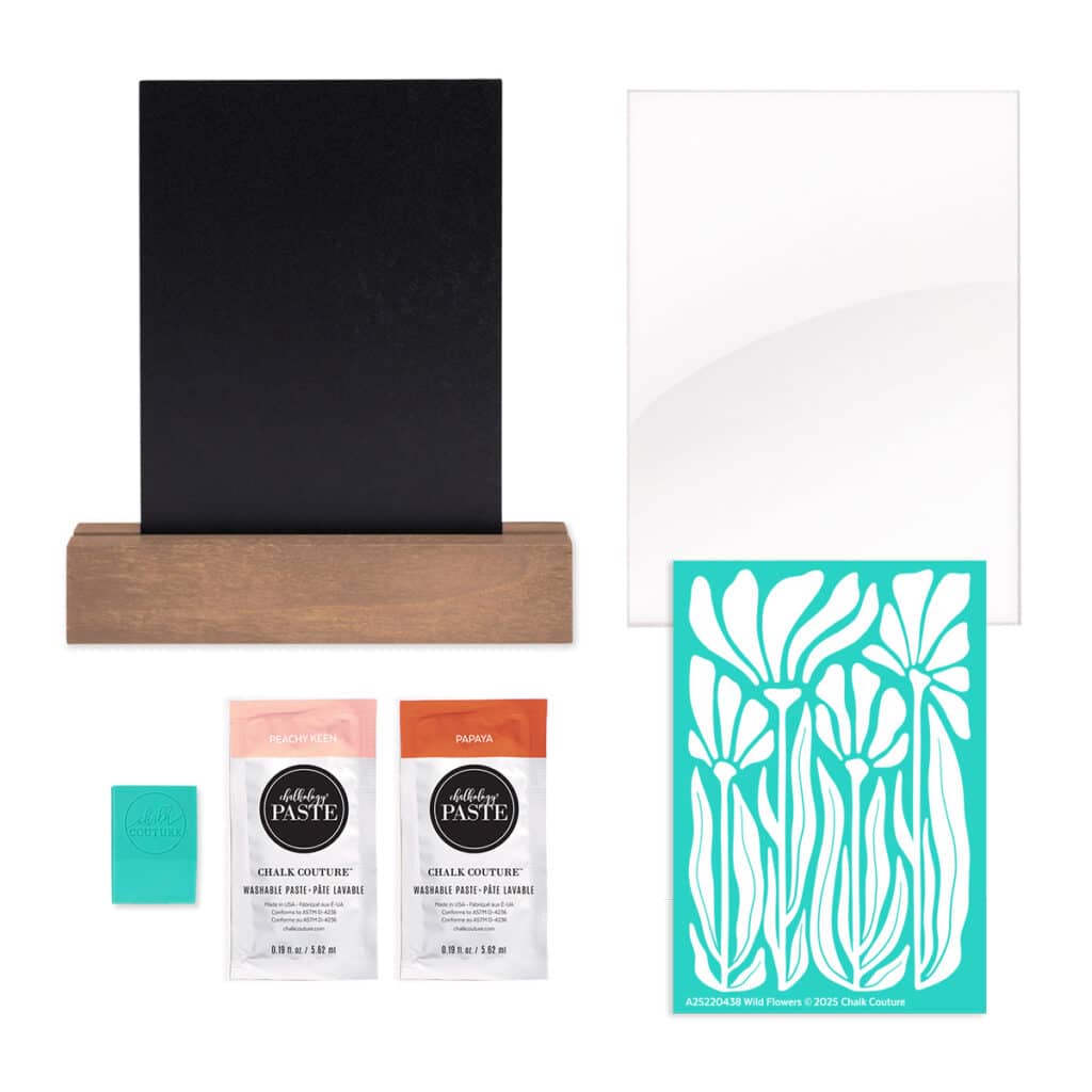 A photo of the contents of the Chalk Couture Wild Flowers Try Me Kit including a black board and base surface, an acrylic surface, the Wild Flowers stencil, two packets of Chalkology Paste in Peachy Keen and Papaya, and a squeegee for the blog post "Try your hand at chalking with a Chalk Couture Try-me Kit".