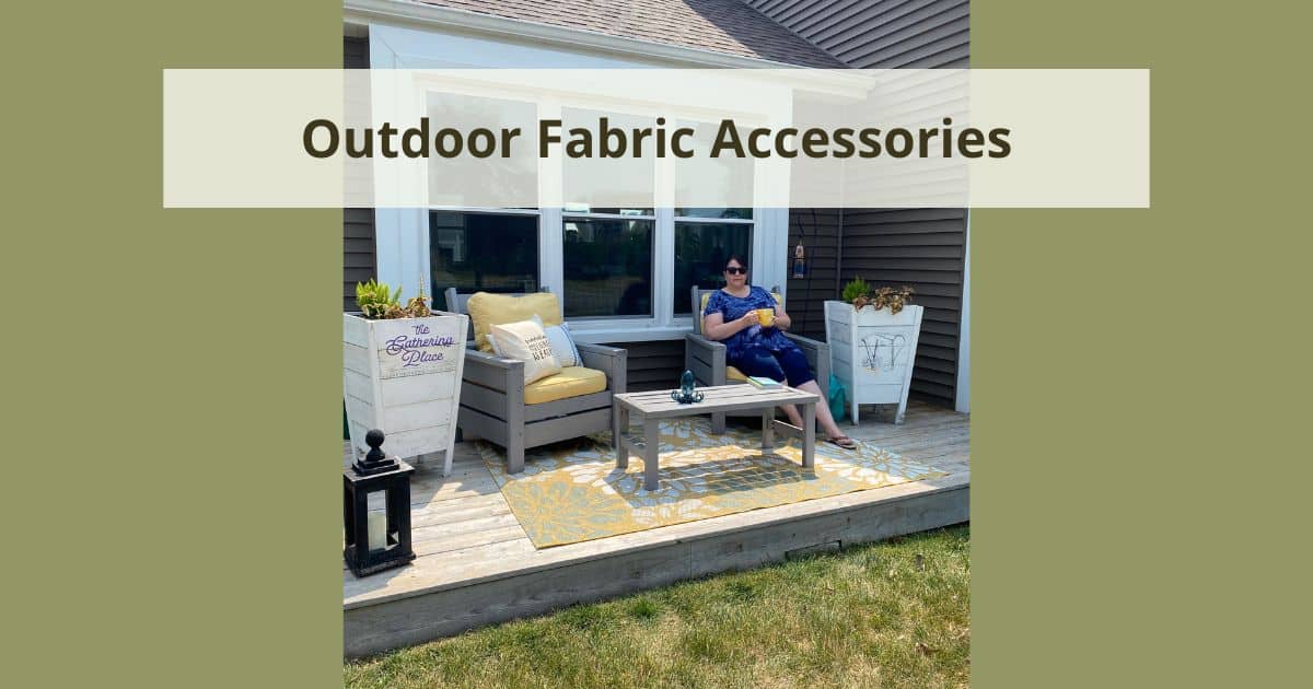 A photo of a woman on a porch holding a yellow coffee cup with grey furniture, yellow chair cushions, canvas pillows, two white tall planters and a black wood lantern for the blog post "Outdoor Fabric Accessories".